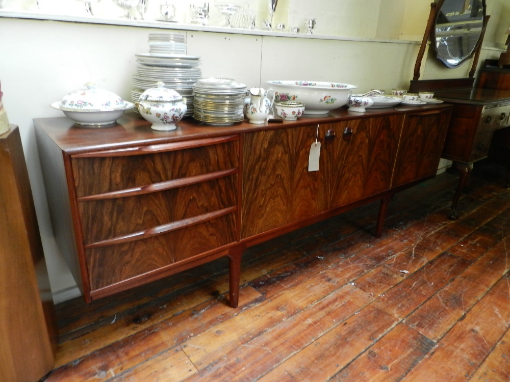 A large rosewood sideboard with an arrangement of cupboards and drawers, bears label for A H