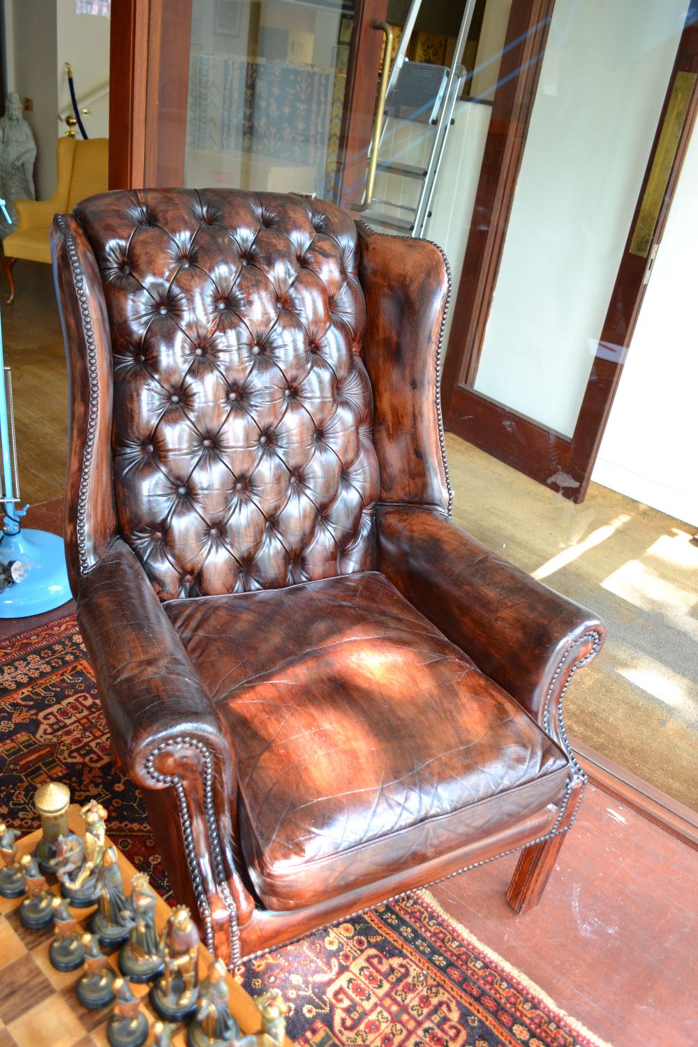 A pair of tan leather button back upholstered wing armchairs raised on moulded square section