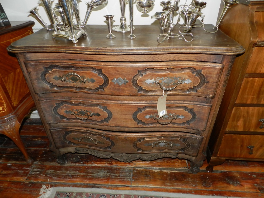 A continental oak serpentine fronted chest of three drawers raised on moulded supports.
