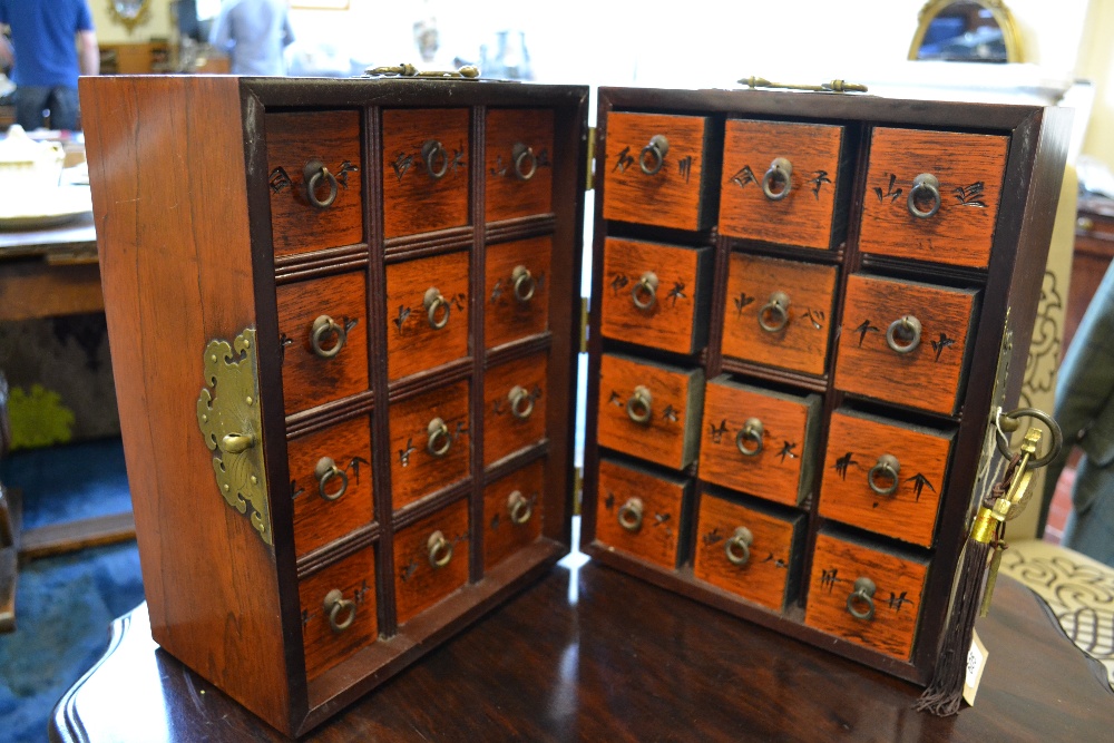 A Chinese metal mounted hardwood table top cabinet opening to reveal 24 spice /tea drawers