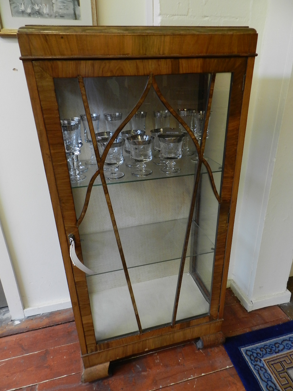 A 1920's rectangular walnut veneered glazed sides and glazed astral hinged door above four