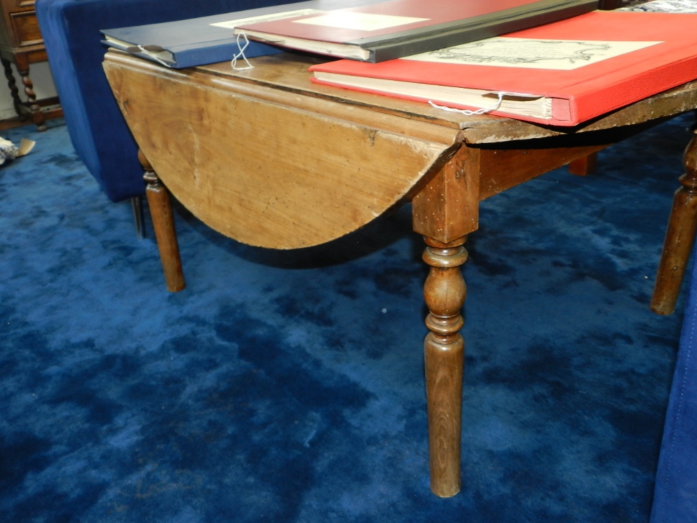 A French drop flap low table circular form raised on turned supports.