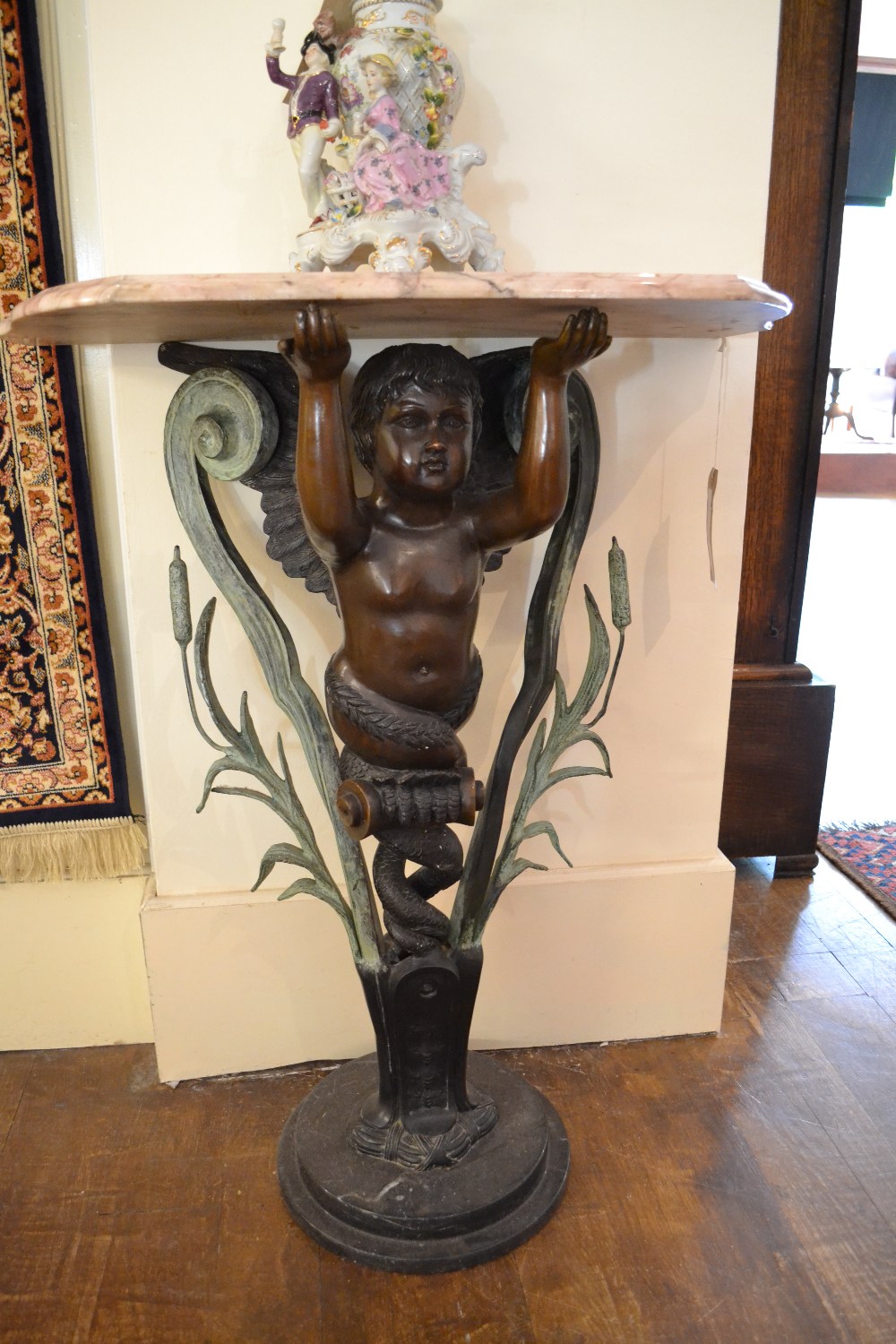 A French marble topped bronze console table in the form of a cherub raised on a marble base.