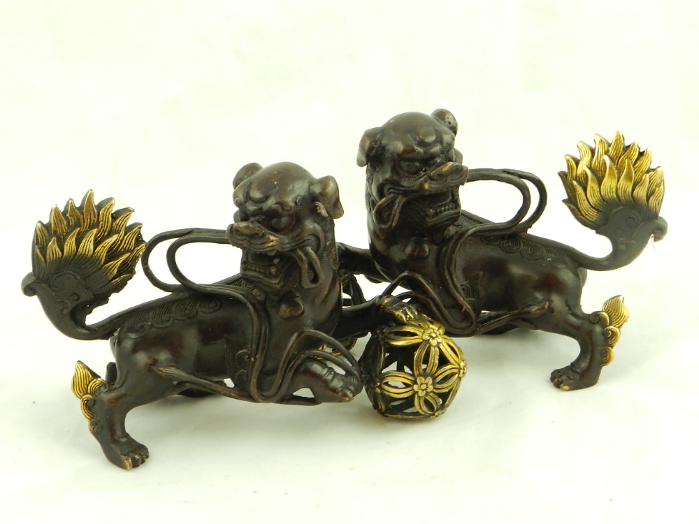 A pair of Chinese bronze dogs of Fo the well cast figures with gilt highlights.