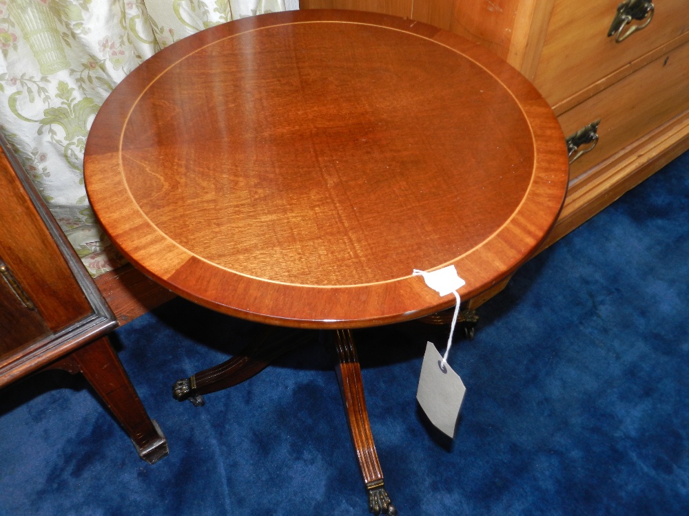 An inlaid cross banded pedestal low table raised on out swept supports with paw casters.