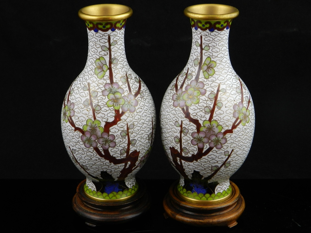 A pair of Chinese cloisonne vases decorated with flowering prunus blossom on a white ground each