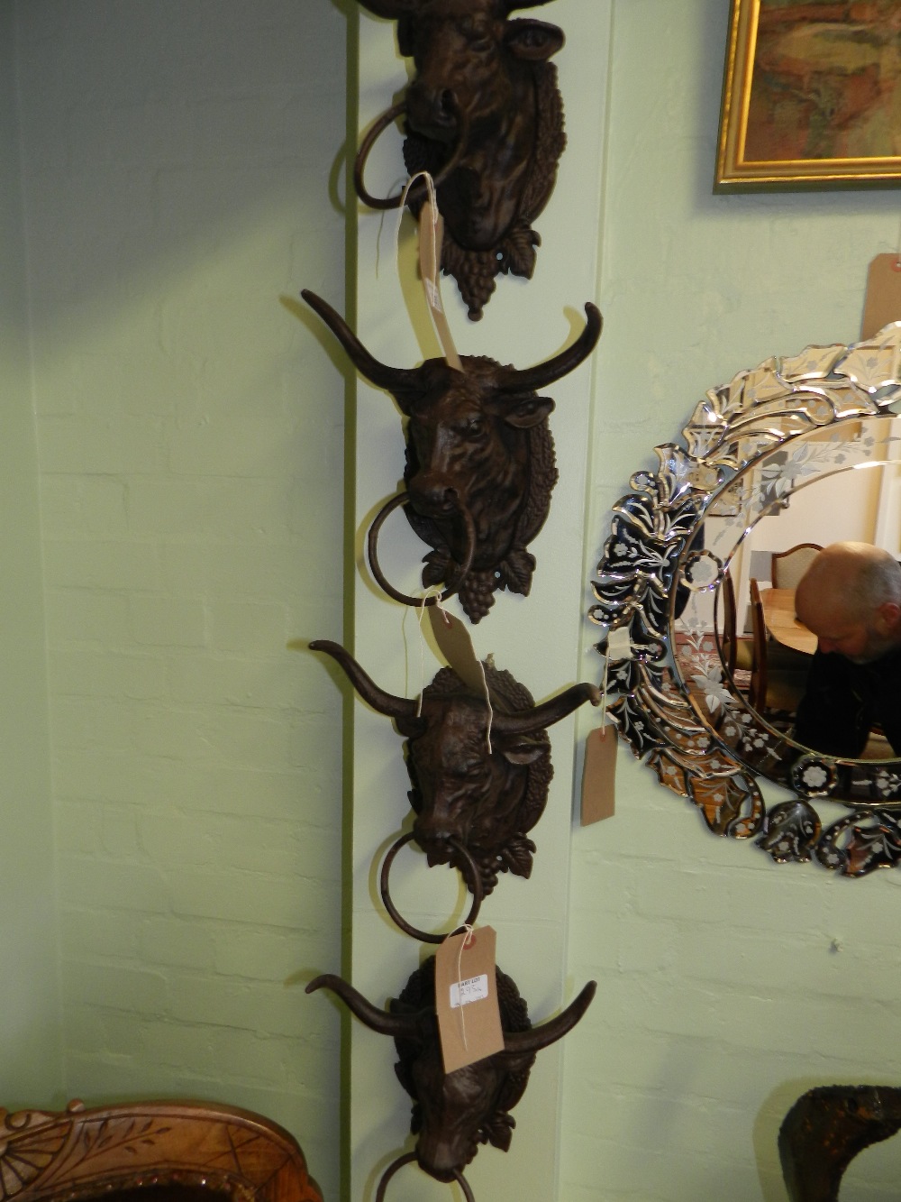 A set of four cast metal bulls heads wall mounts with rings through their noses.