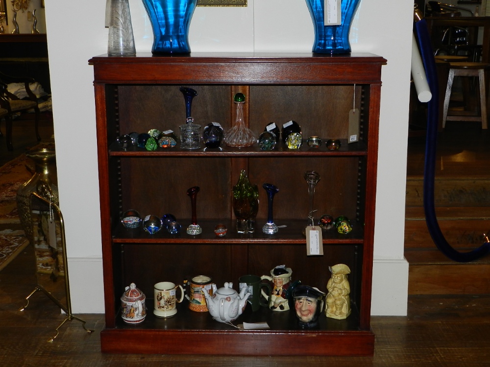 An inlaid mahogany set of floor standing book shelves raised on a plinth