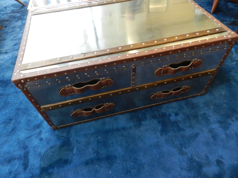 A coffee table in the form of a trunk with polished, metal topped hinged and sides and simulated