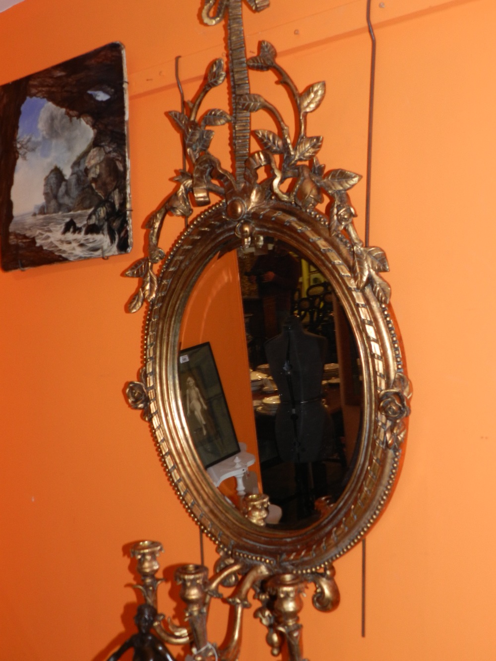 A pair of oval girondelles, bevelled mirrors within gilt wood frames with leaf and floral