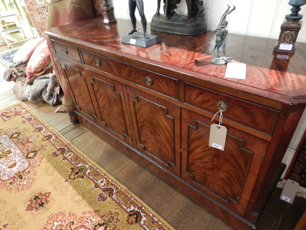 A mahogany side board of three drawers over four cupboard doors raised on a plinth.
