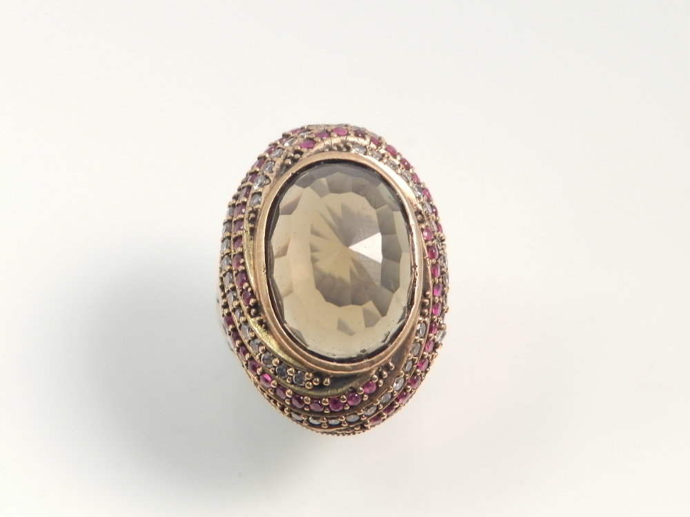 An exotic white metal ring set with faux topaz, rubies and diamonds.