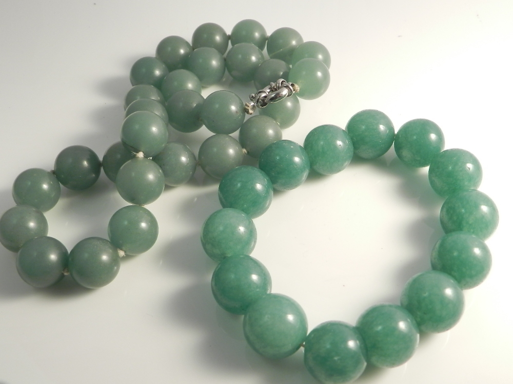 A green jade necklace with white metal clasp along with a matching bracelet.