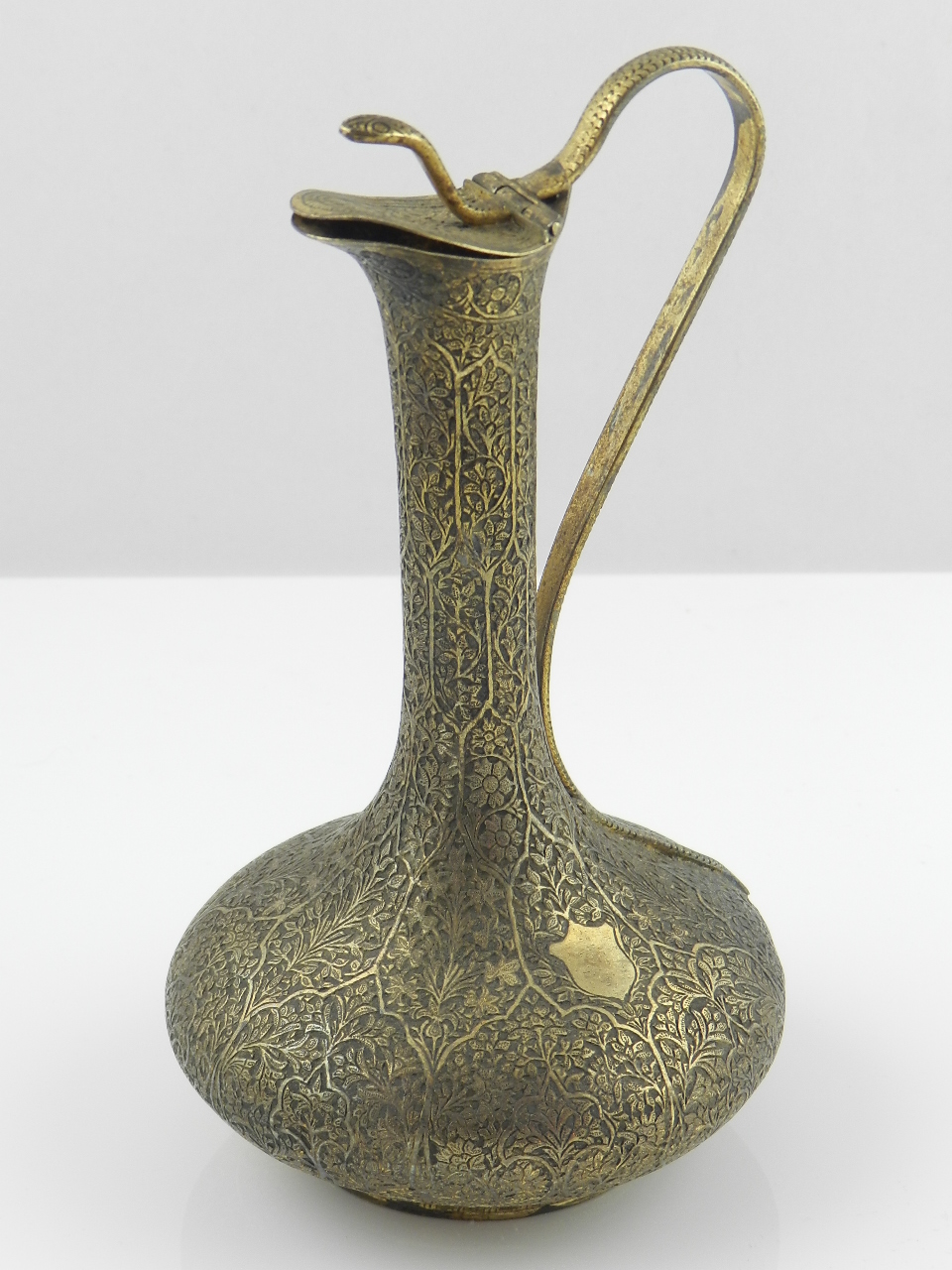 An early 20th century Islamic metal ewer with a cobra head handle and profuse floral decoration