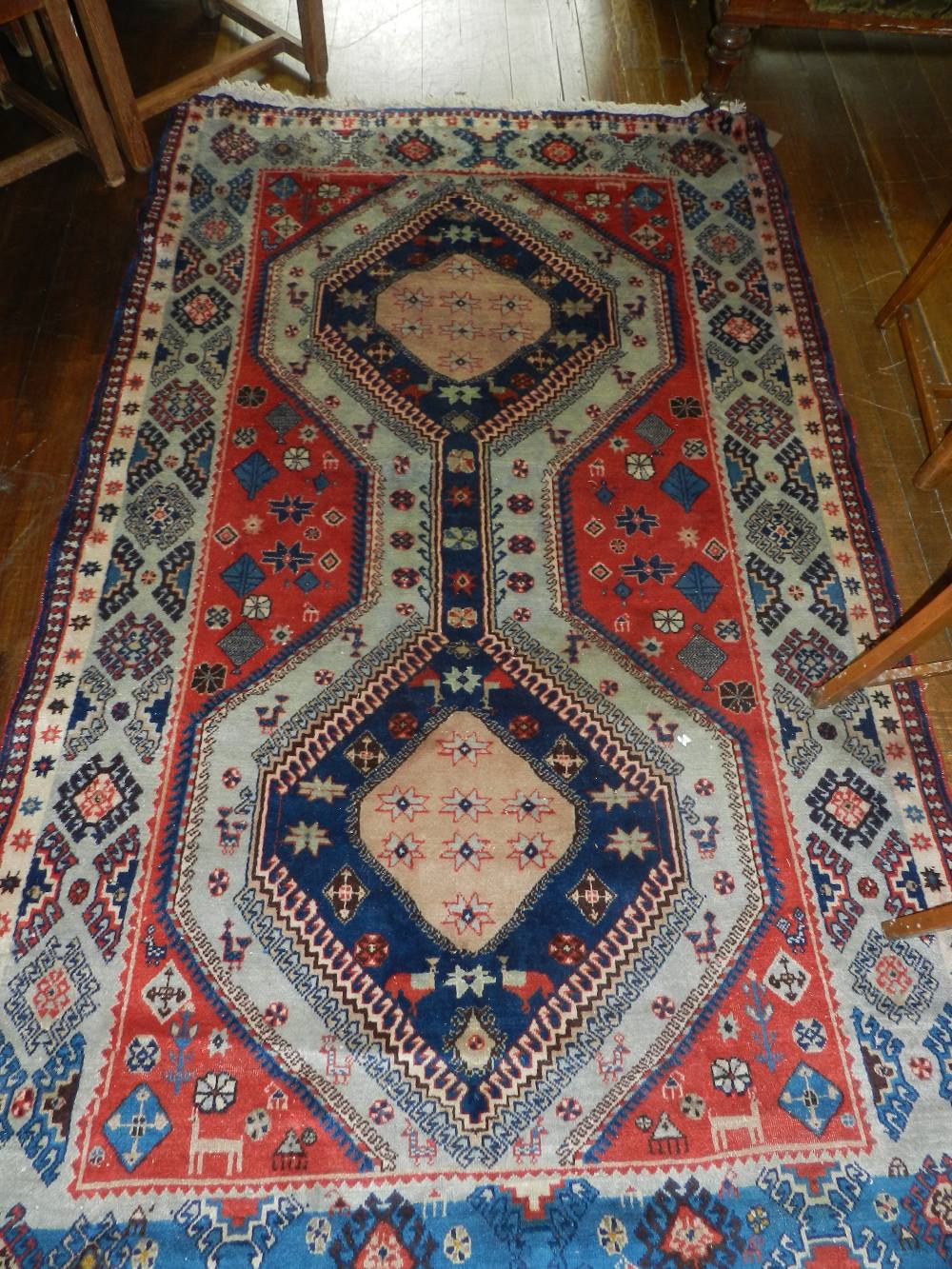 A Persian Heriz carpet having twin pole medallion on a zoomorphic madder ground contained by borders