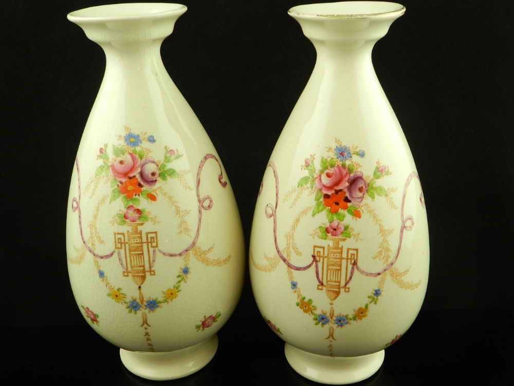 A pair of Crown Ducal porcelain vases decorated with floral trophies on a cream ground