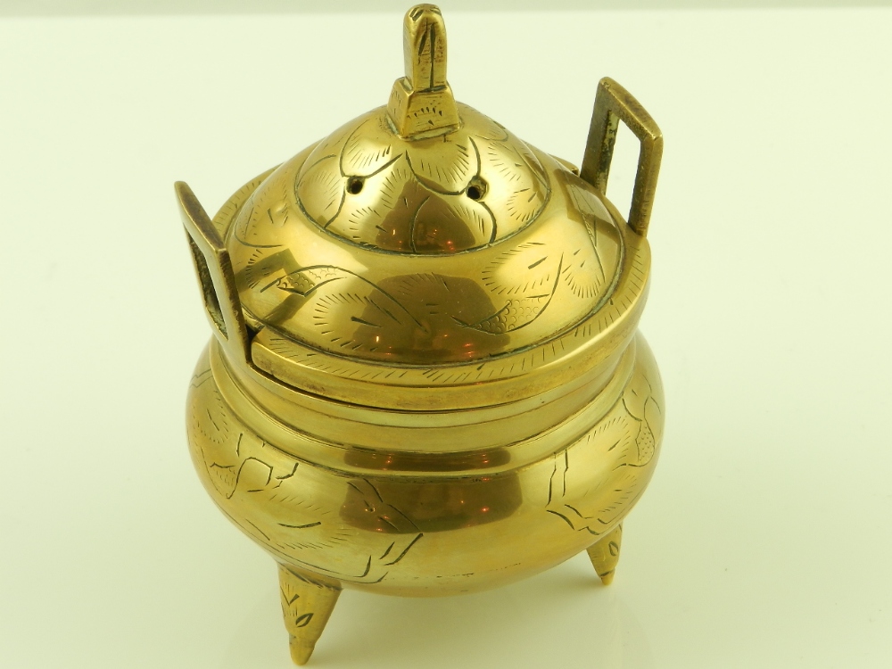 A 20th century Chinese twin handled brass incense burner raised on triform supports bearing