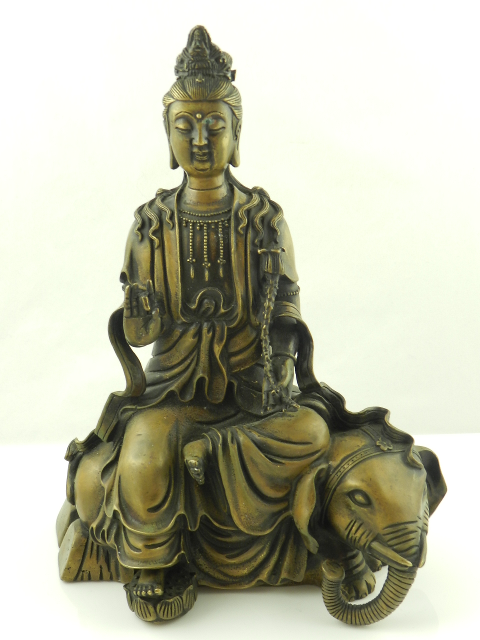 A Chinese bronze model of Guan Yin seated on the back of an elephant.