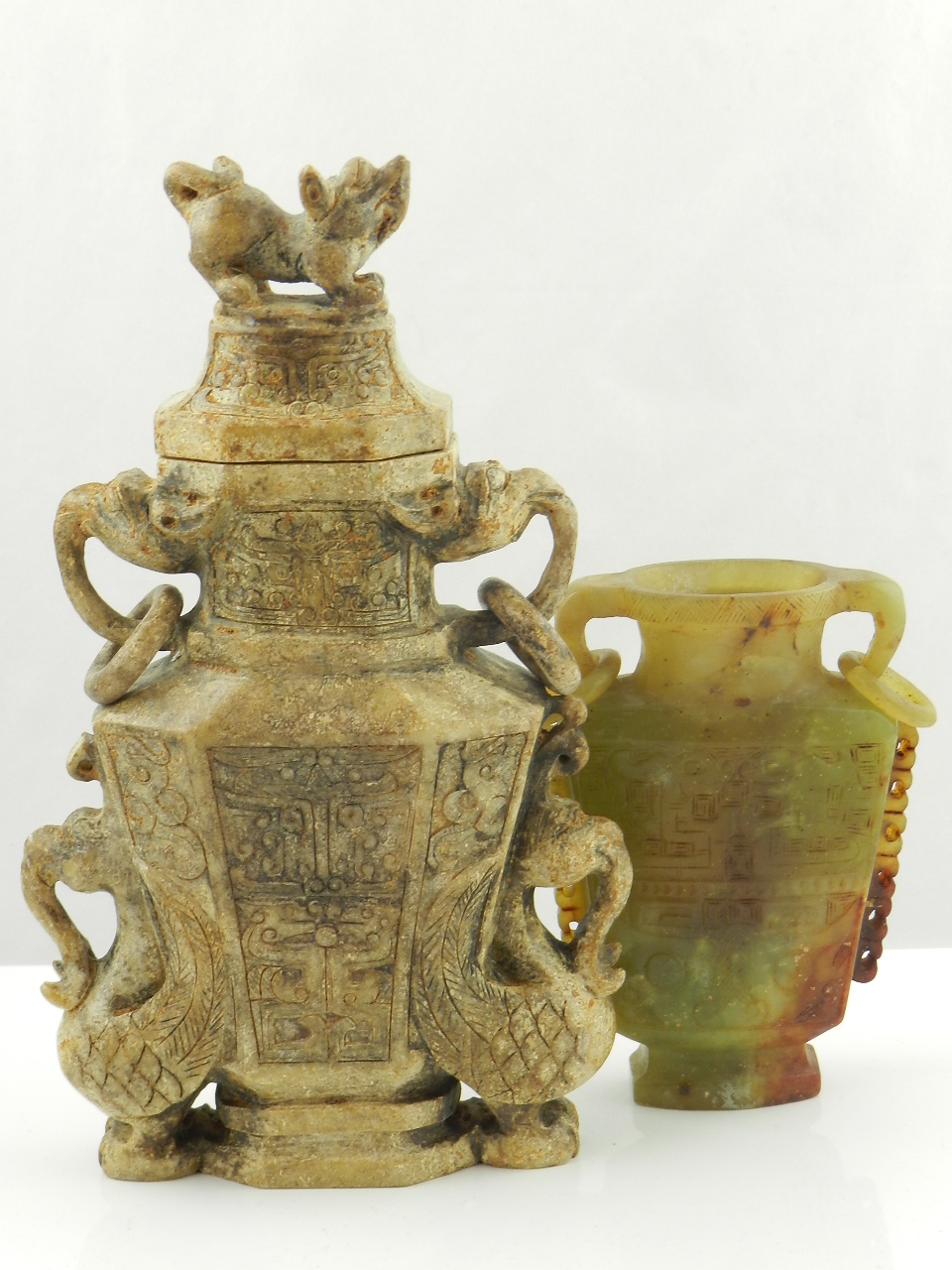 A carved Chinese stone handled pot and cover along with a twin handled carved green jade vase