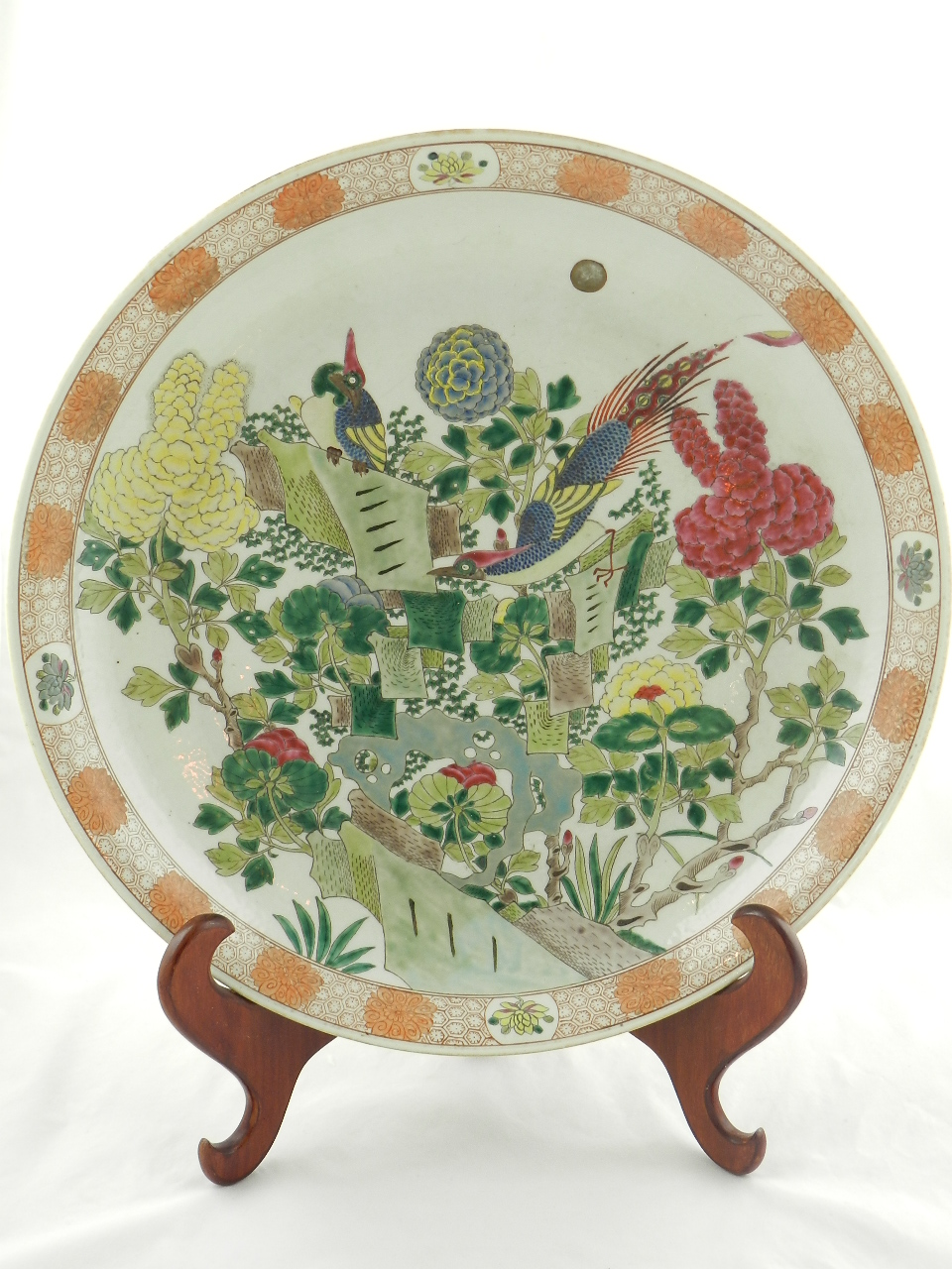 A large Chinese porcelain charger enamel decorated with stylized bird in tree designs on a cream