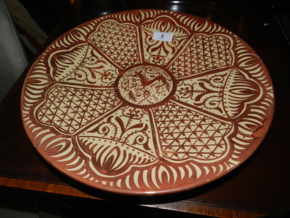 A Spanish lustre ware copper glazed charger with raised central boss decorated with a stylized