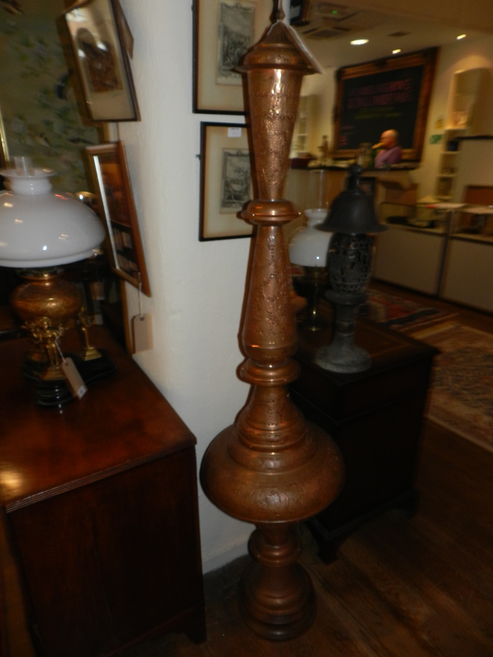 An early 20th century pierced copper standing lamp of baluster form chased with bands of stylized