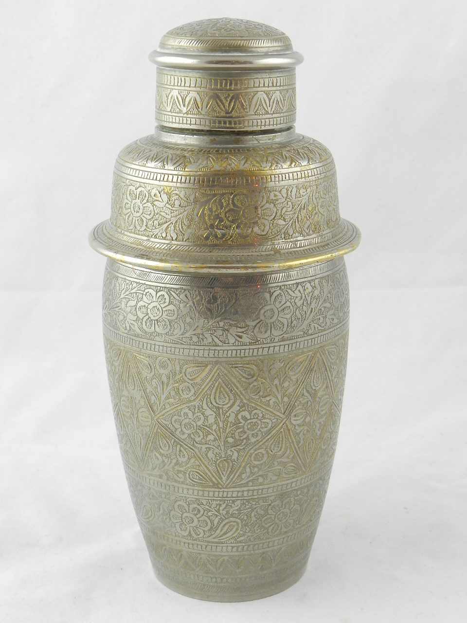 A heavy silver plated cocktail shaker intricately decorated with Islamic style engraving