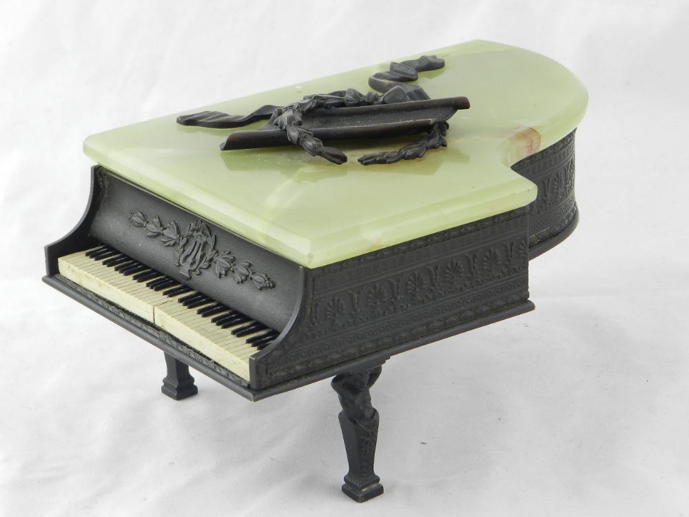 A musical box in the form of a grand piano the hinged onyx lid revering a compartment for