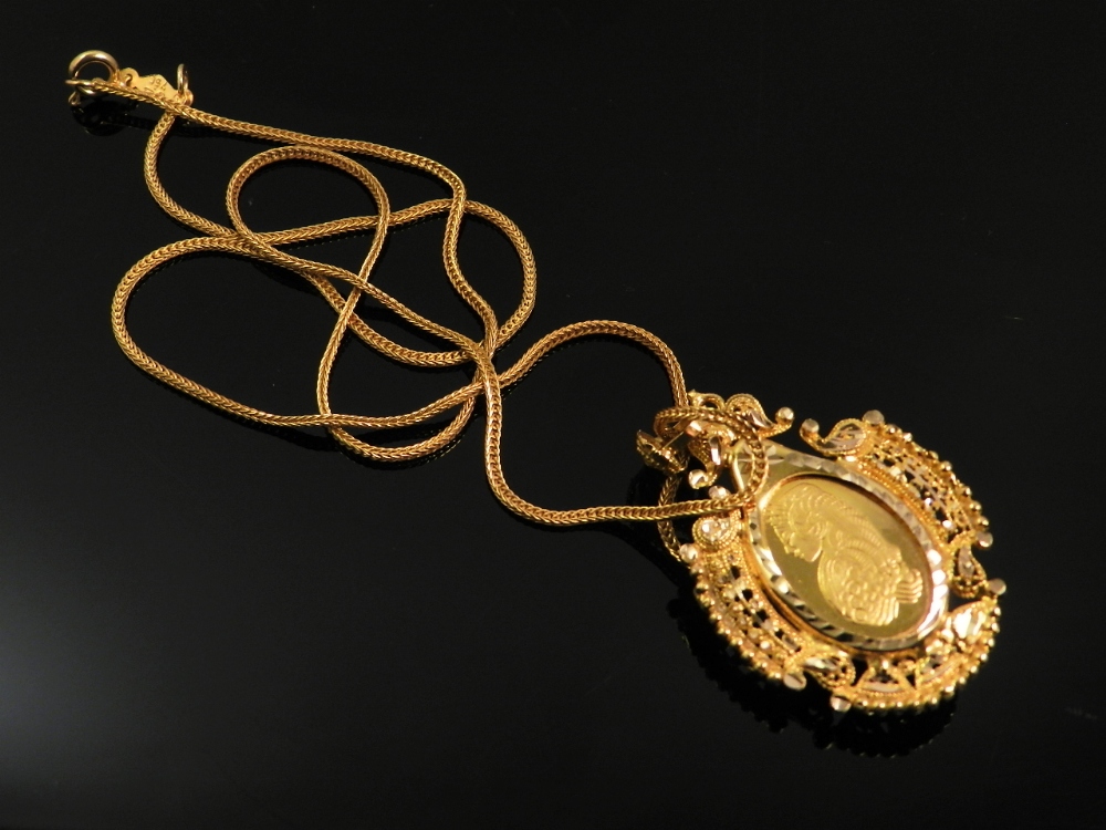 An 18ct gold Persian pendant engraved with a figure in profile within a pierced and beaded