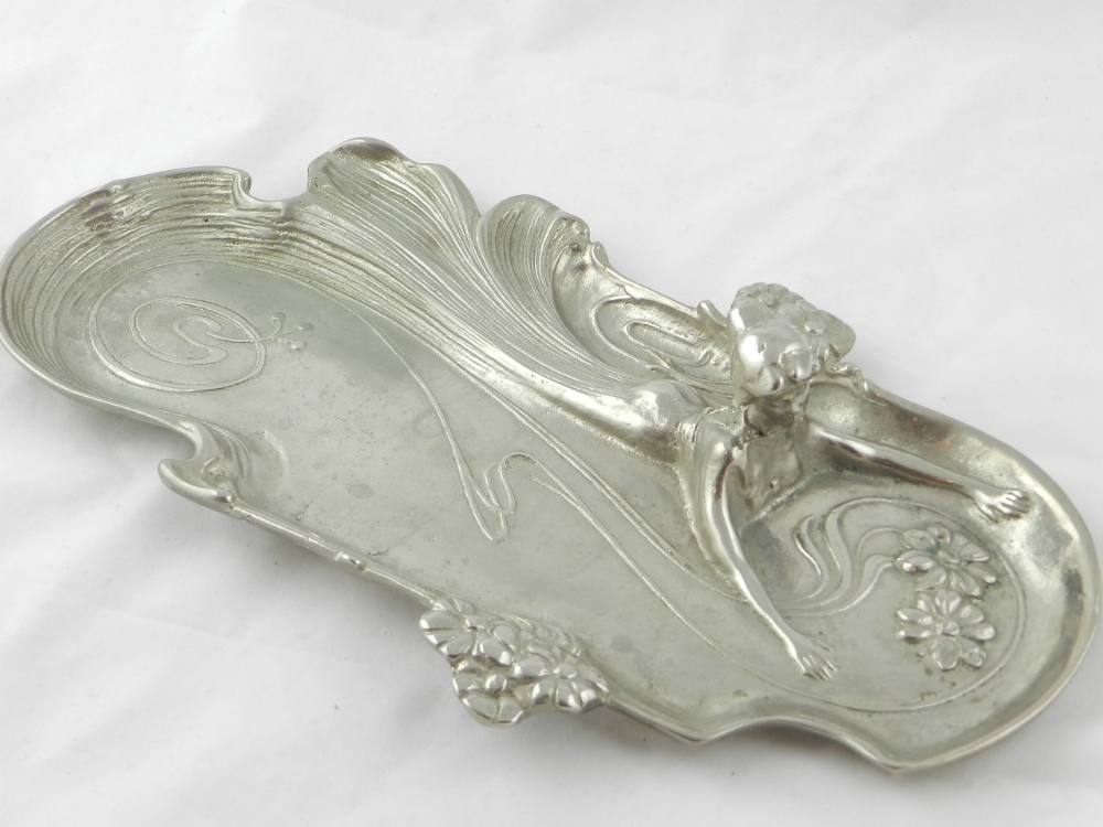 An art nouveau style white metal pen tray relief decorated with a spiralling woman.