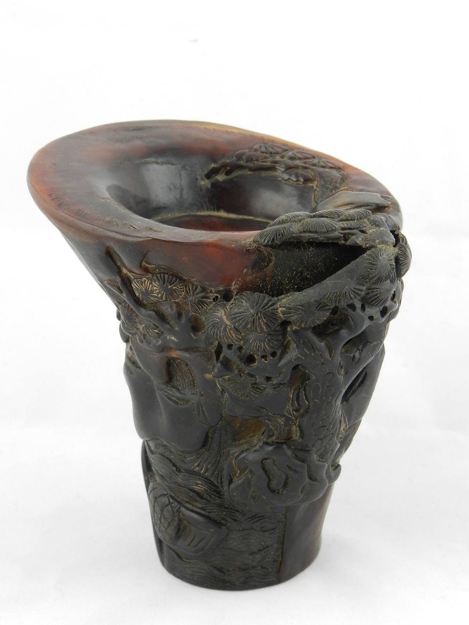 A Chinese horn libation cup carved with figures and vegetation