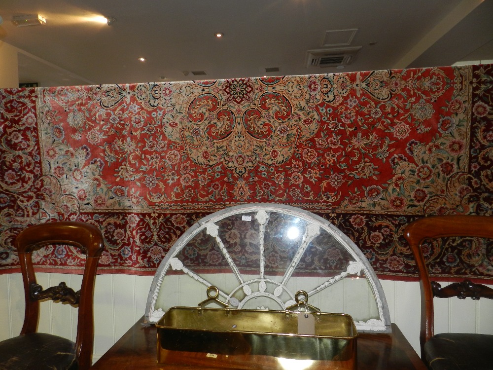 A fine Persian silk carpet made in Qum with central floral rosettes against a peach ground within