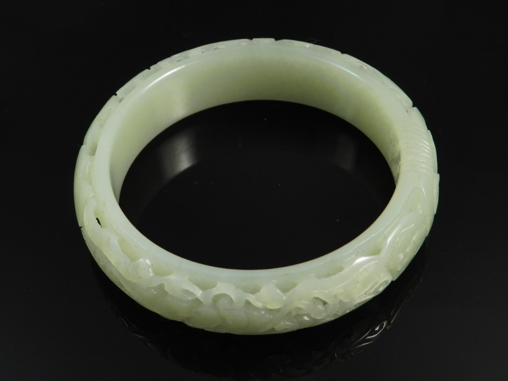 A Chinese pierced celadon jade bangle carved leaves and flowers