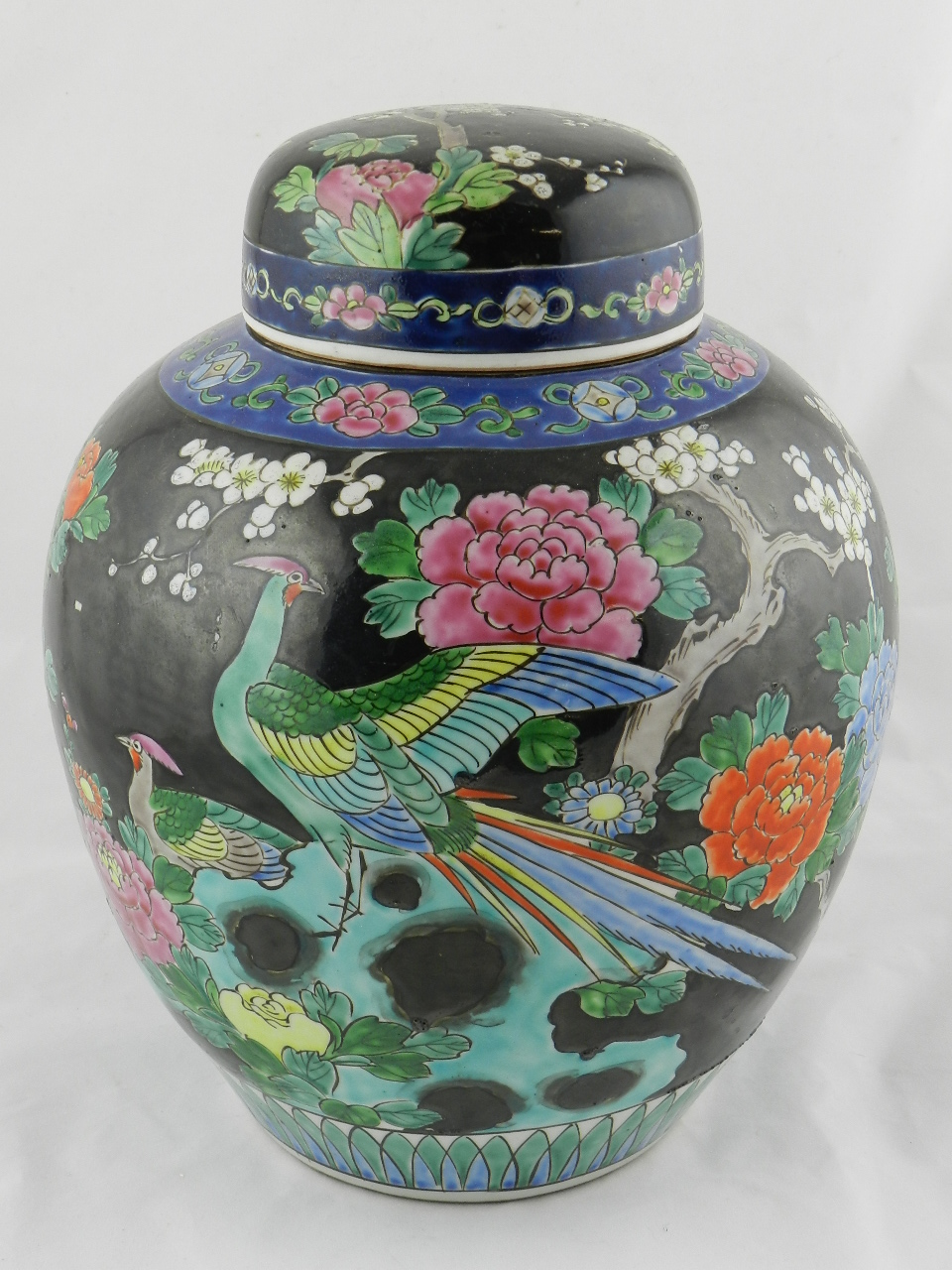 A large famille noir ginger jar decorated with flowers and bird life.