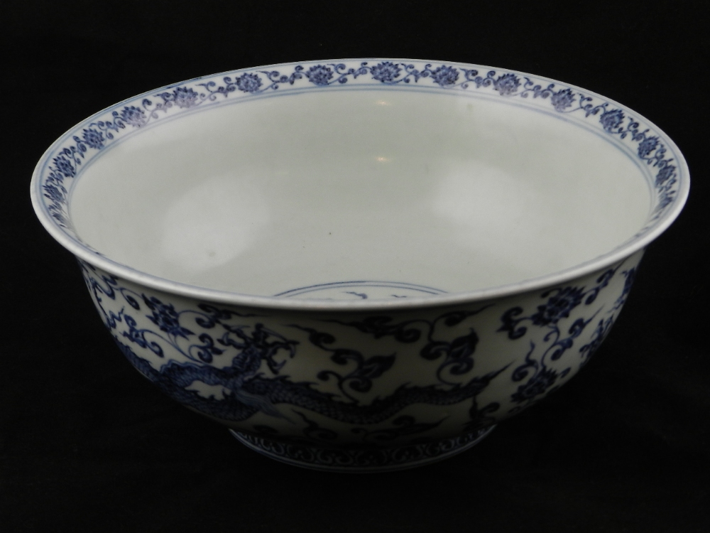 A Chinese blue and white bowl decorated with dragons, flowers, leaves and stylized clouds, having