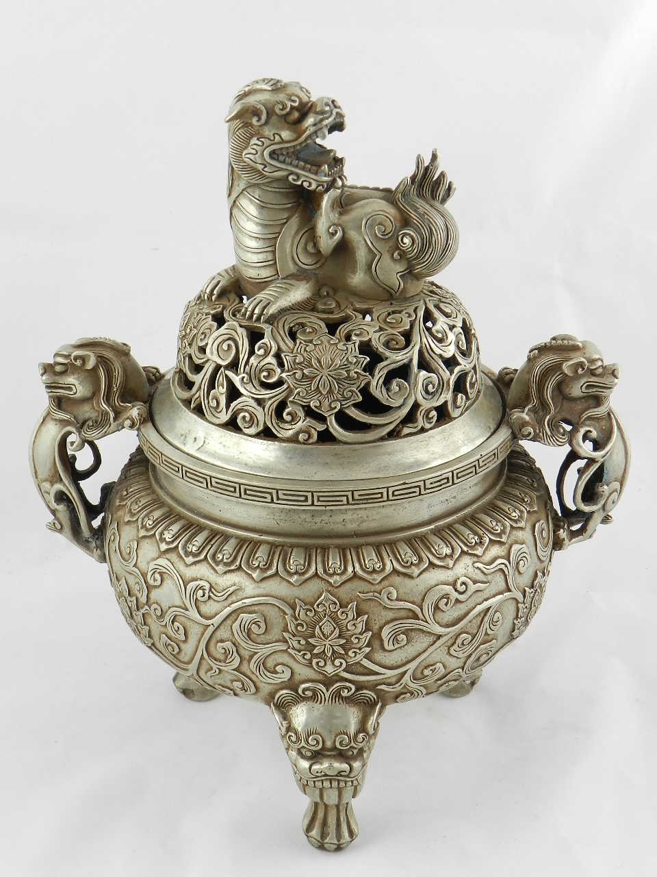 A 20th century white metal inscense burner of cauldron form chased with flowers and scrolls, with