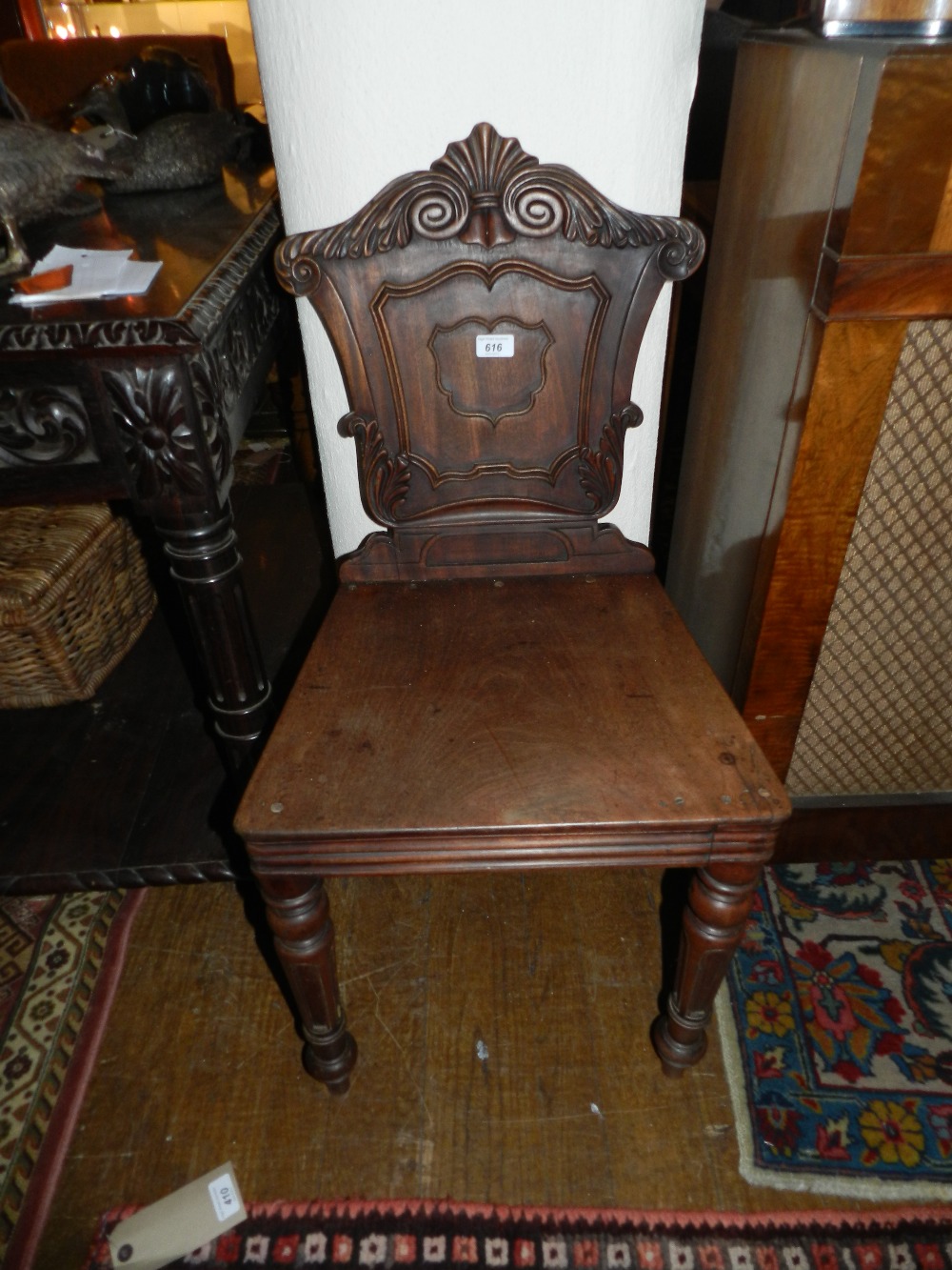 A 19th century carved mahogany hall chair raised on turned supports