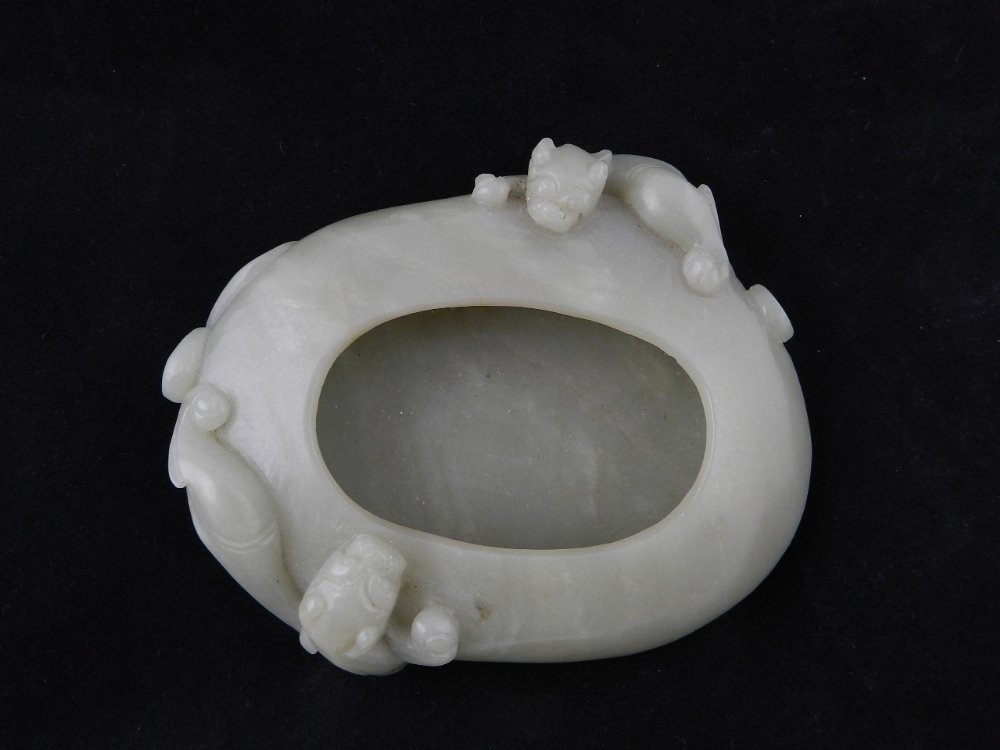 A Chinese celedon jade inkwell having carved twin dragon decoration.