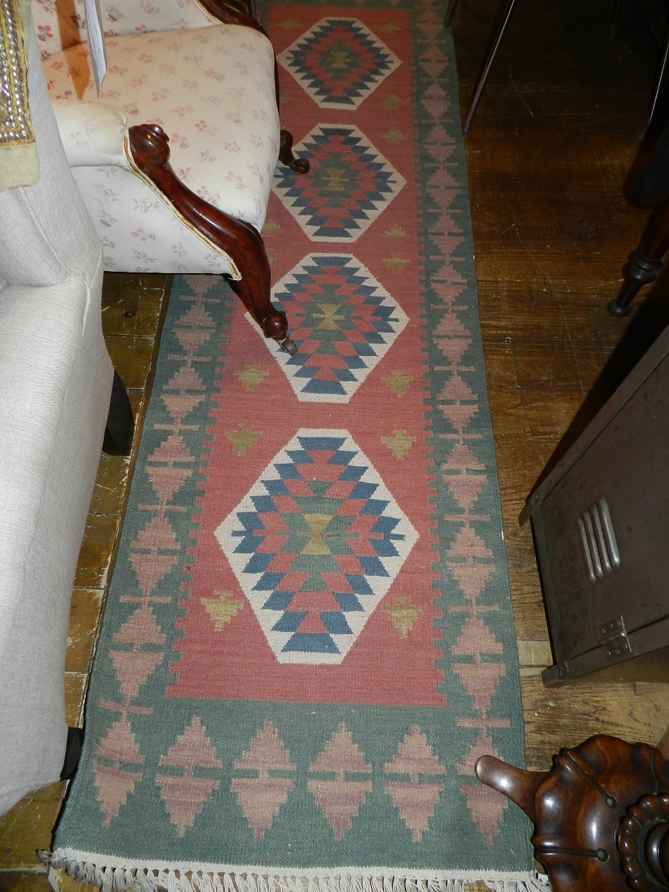 A Persian runner geometric design blue, green and ivory design on a coral ground.