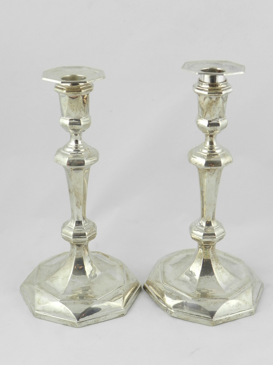 A pair of filled silver table candlesticks with  faceted knobbed stems on raised octagonal bases,