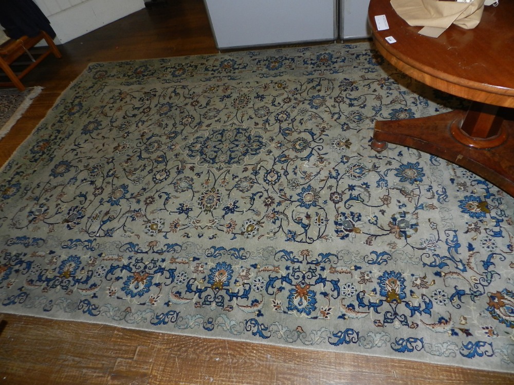 A Kashan rug having central medallions on a floral decorated pale blue ground 293x213
