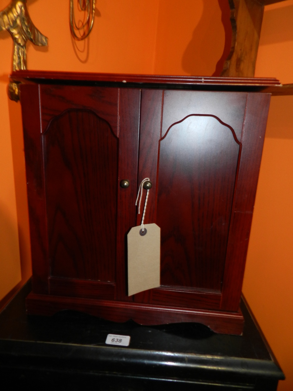 A table top jewellery chest with rising hinged lid and panelled doors open to reveal seven drawers.