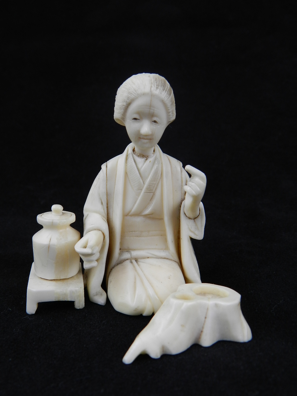 An Oriental ivory figural group formed as a kneeling lady,a pot on a small table at her side late