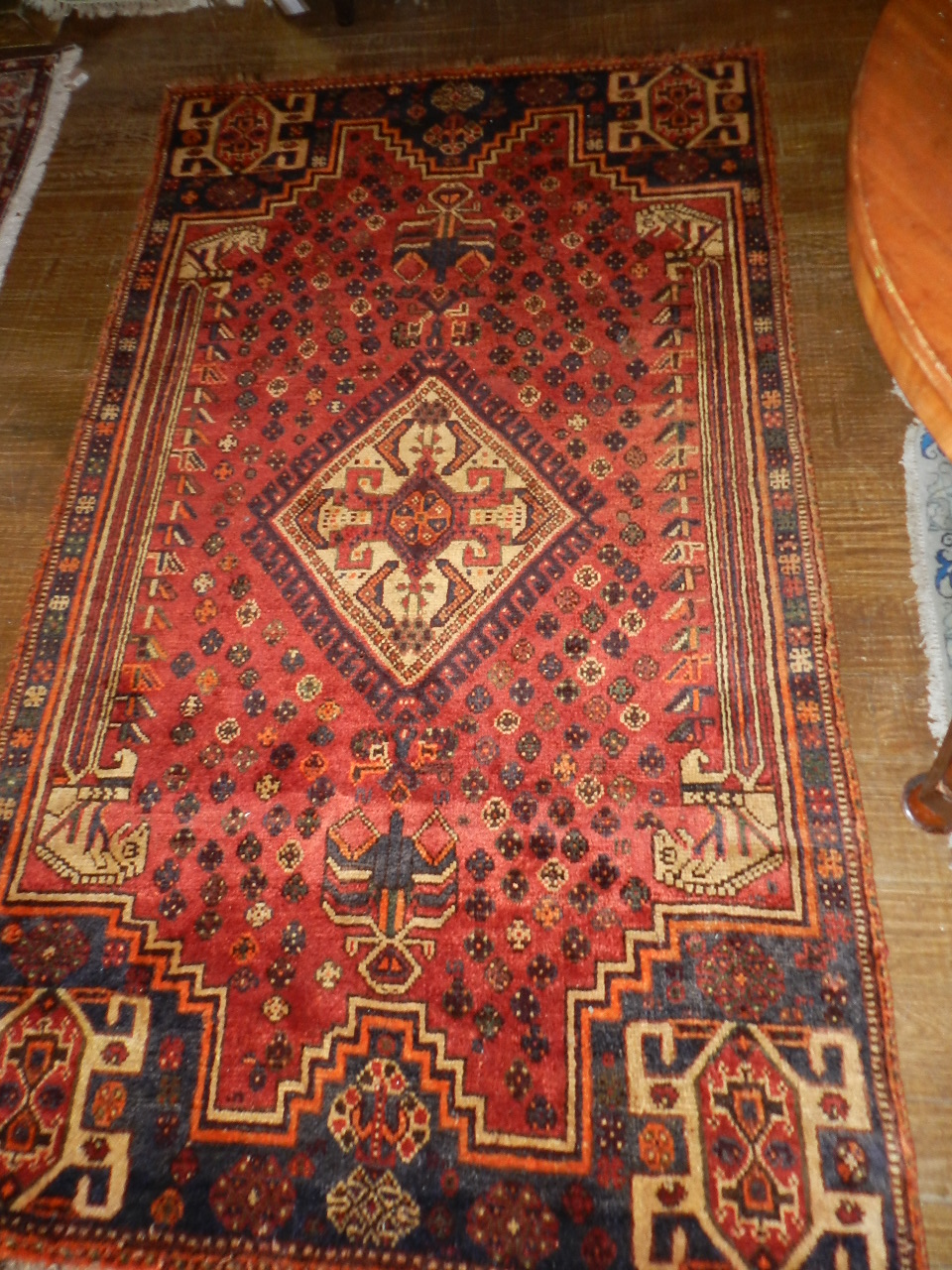 A Shiraz rug with central geometric medallion on a madder ground decorated with guls and