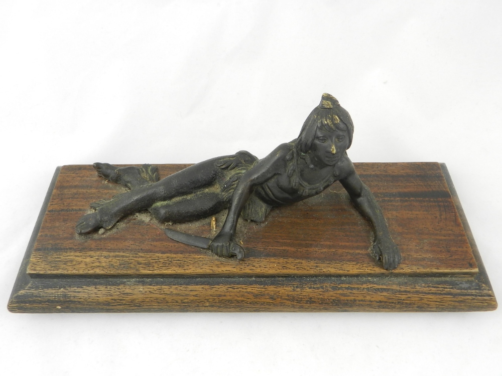 An Indian bronze recumbent warrior on a hardwood base.