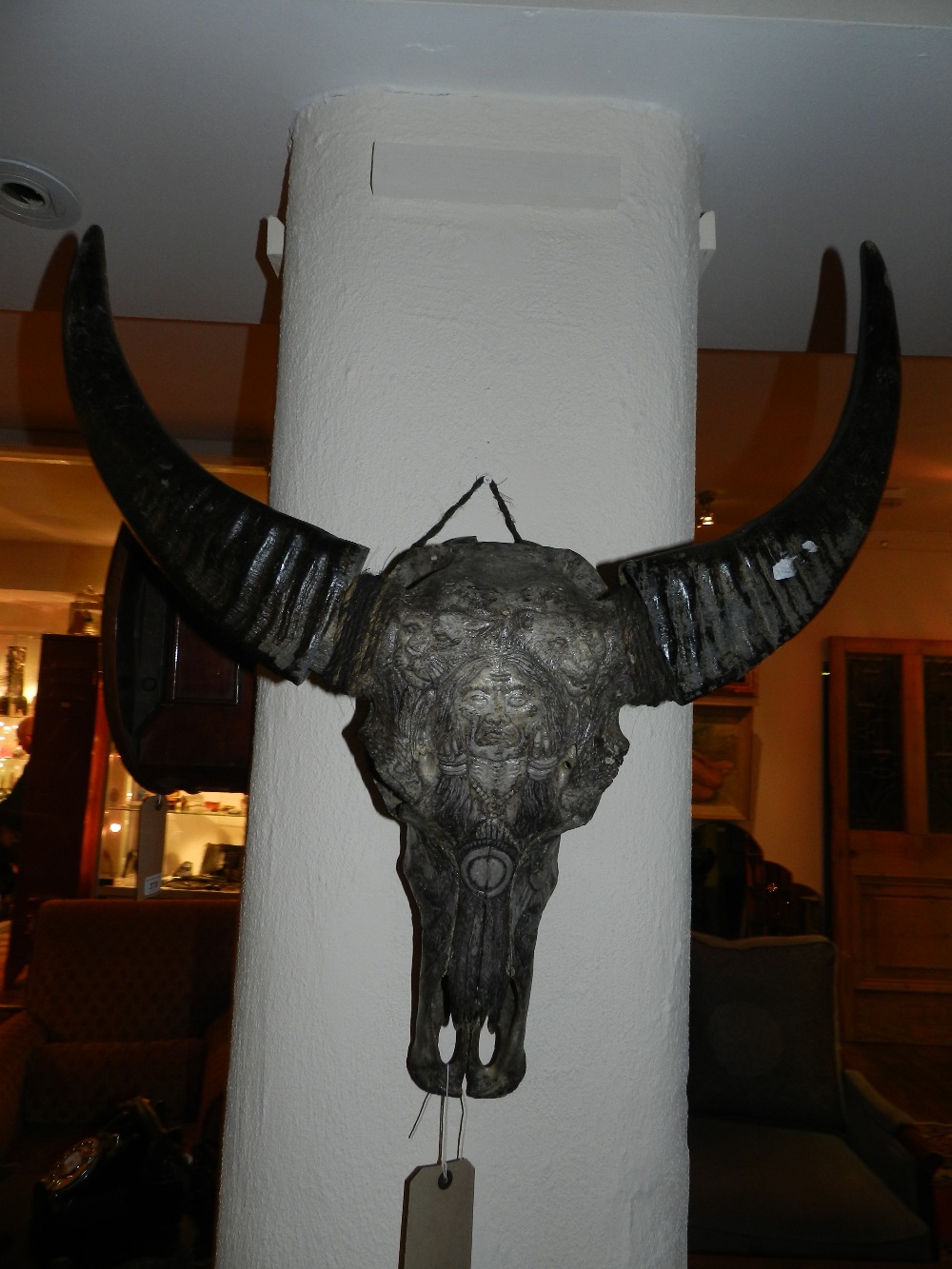 A wall mounted animals skull having carved red Indian and animal decoration with detachable horns