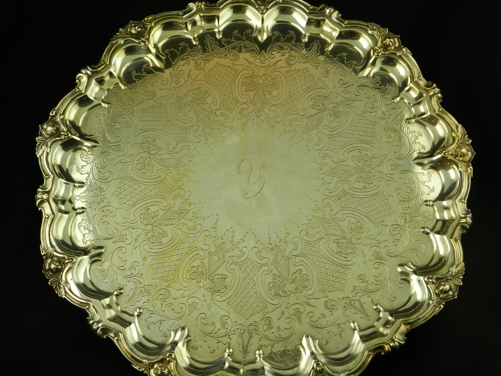 A large silver plated salver in the 18th century style and raised on three scroll supports.