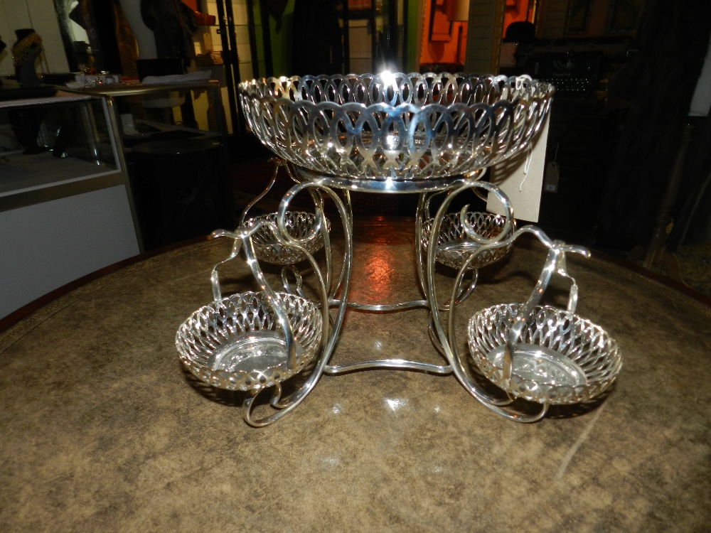 A silver plated epergne of pierced circular form on scrolling supports and four suspensory baskets.
