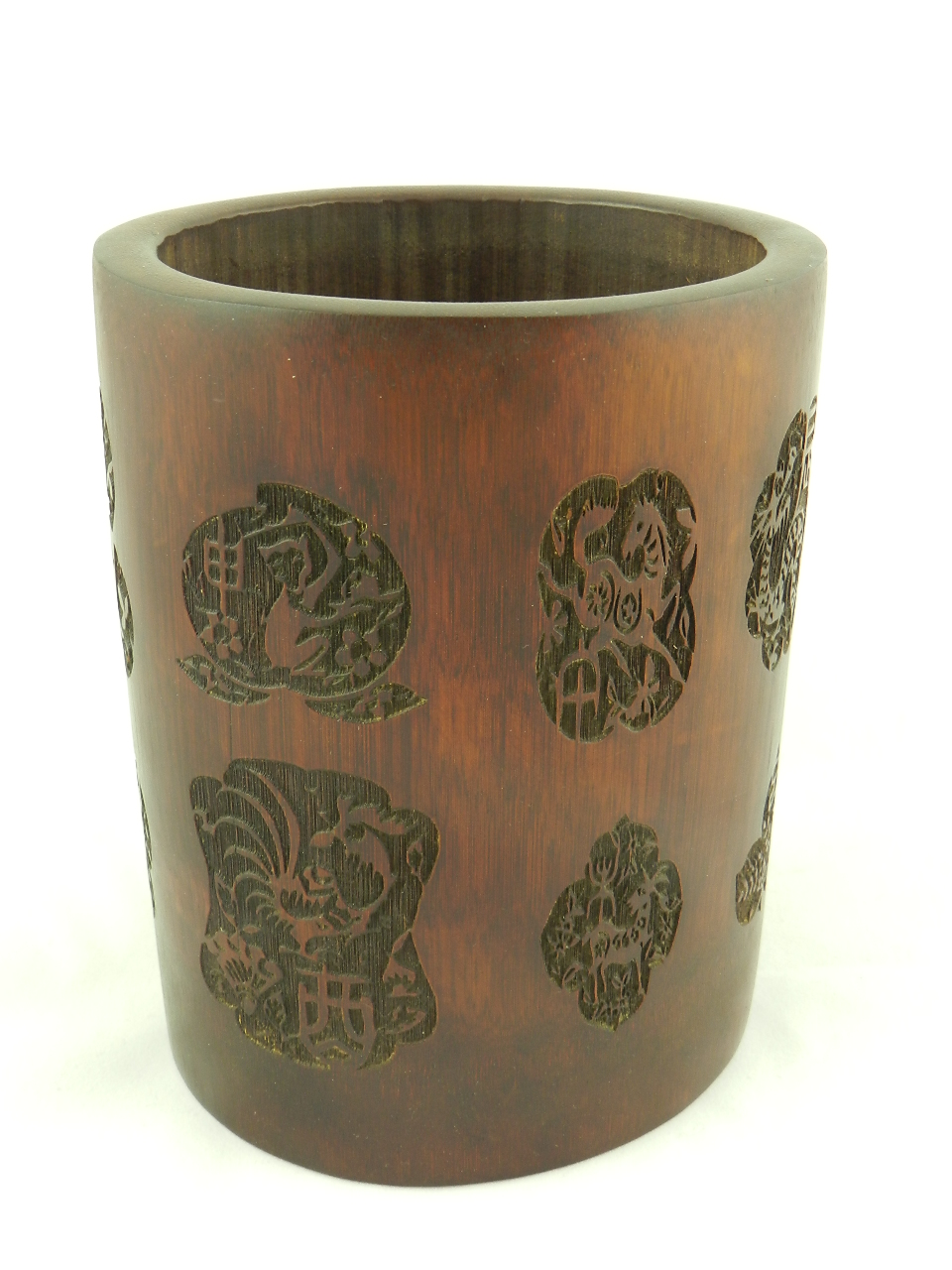 A carved bamboo brush pot, decorated with Chinese emblems.