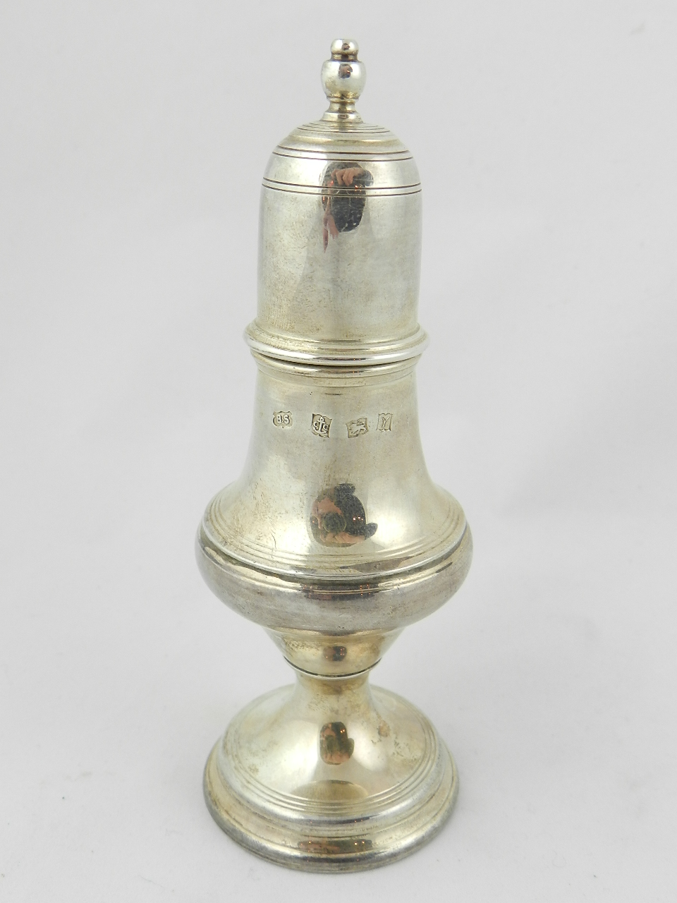 A George III style silver pepperette of baluster form with domed pull off cover